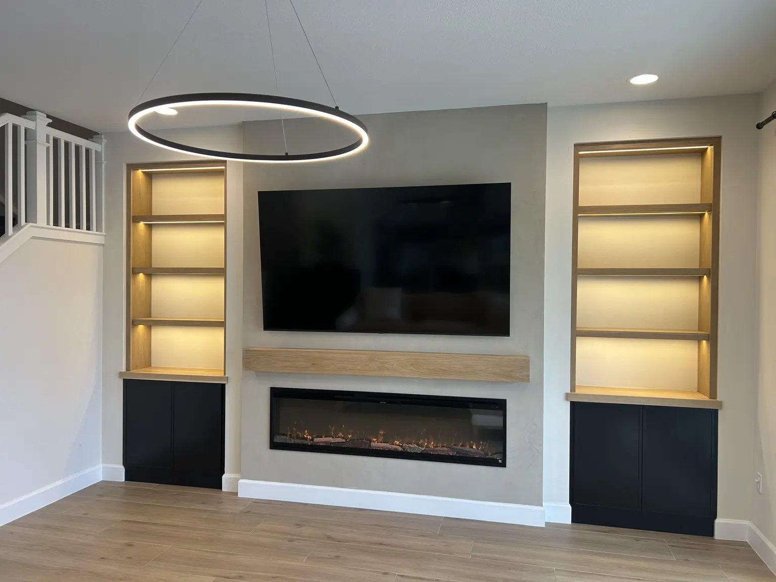 Interior fireplace wall with television, white oak mantle and illuminated built-in shelving
